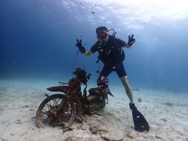 水中に沈んでいるバイクに1人のダイバーがまたがっています