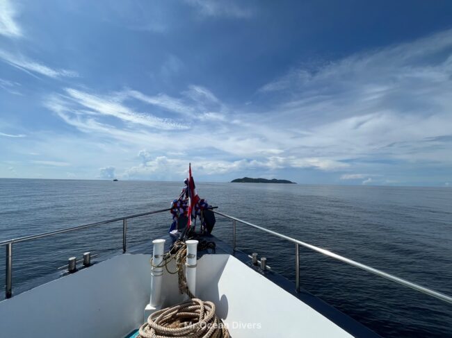 青い空の下、船の船首が島の方に向いています。