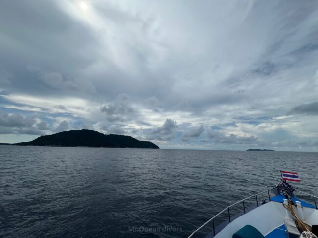 雲の下にラチャノイ島が見え、タイの国旗がある船首が見えます。