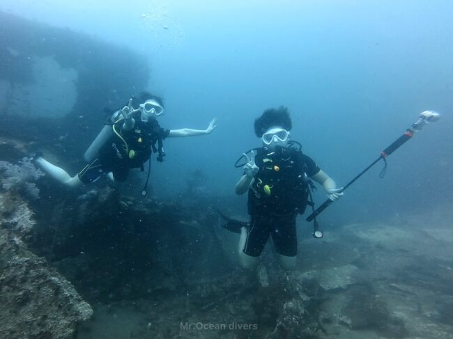 沈船の上で2人のダイバーはピースサインをしています