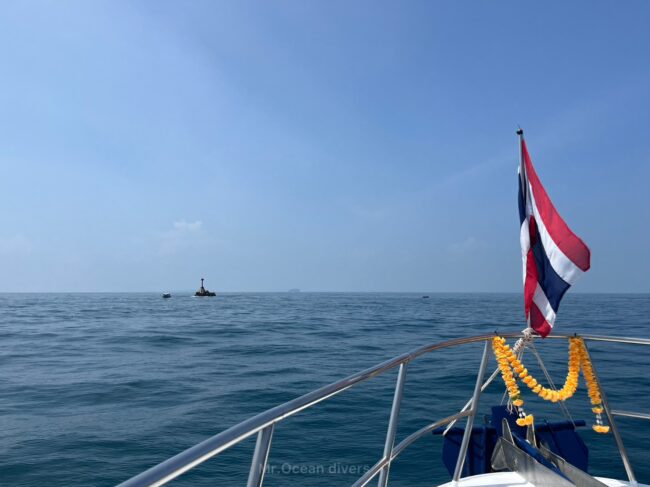 船の船首にはタイの国旗があり遠くに海から出ている岩が見えます