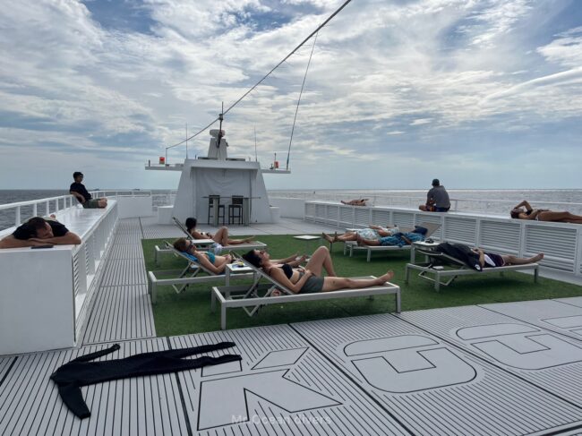 船の屋上で日光浴をする人たちが見えます