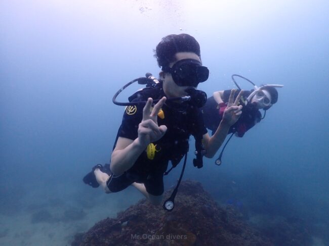 2人のダイバーが泳いでおり1人がピースサインをしています