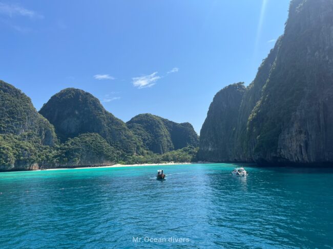 島に囲まれた奥に小さなビーチと小さな船が2台見えます