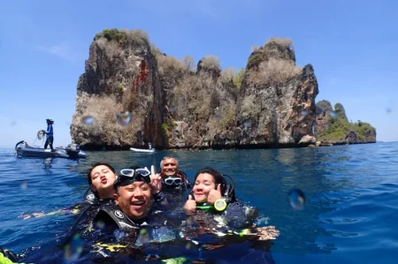 プーケットでダイビングクルーズに参加している4人のダイバーが海に浮いて笑っているのが見えます